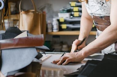 A person skillfully cuts fabric in a workshop, showcasing craftsmanship and creativity.